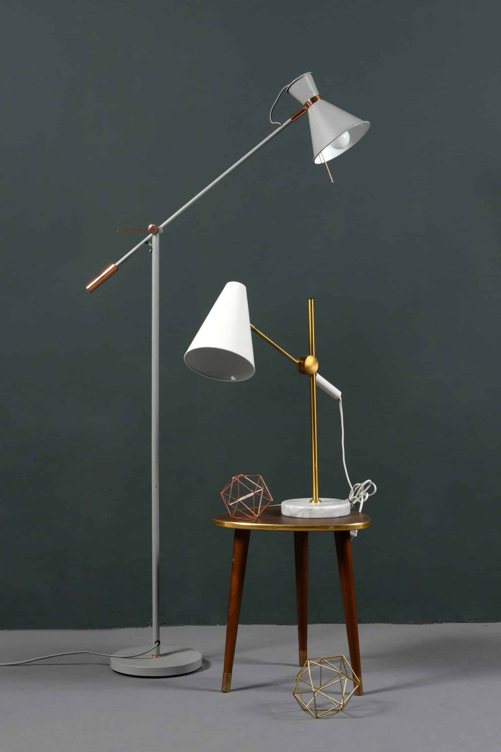 Two vintage anglepoise lamps, one a freestanding floor lamp and the second a table lamp on a stool , against a grey wall indoors
